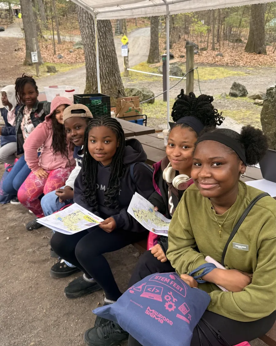 Girls gathered under a tent with their STEM activity materials